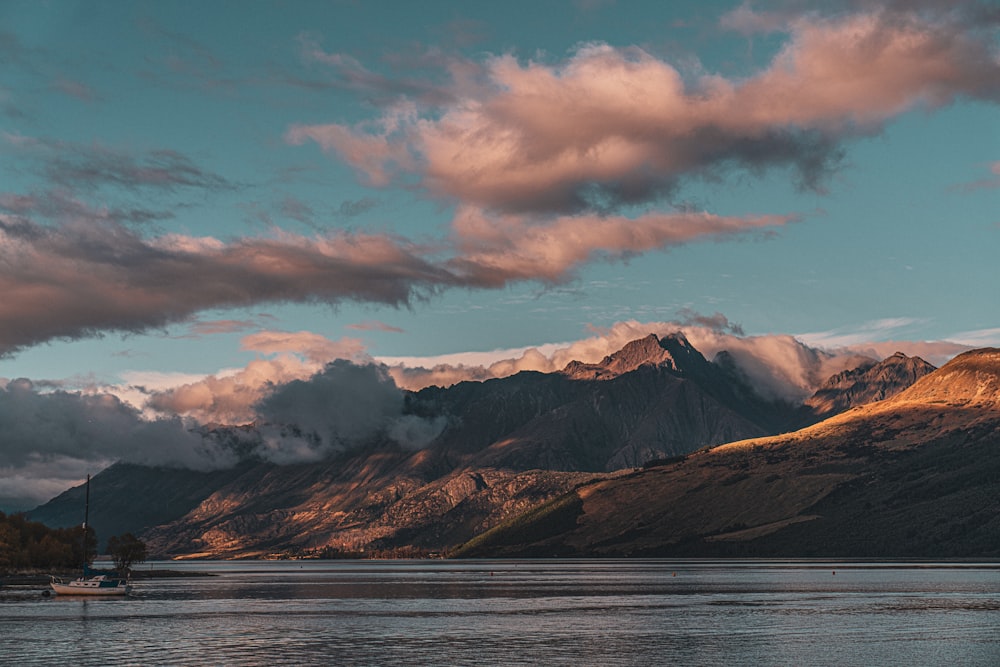 a boat floating on top of a lake under a cloudy sky