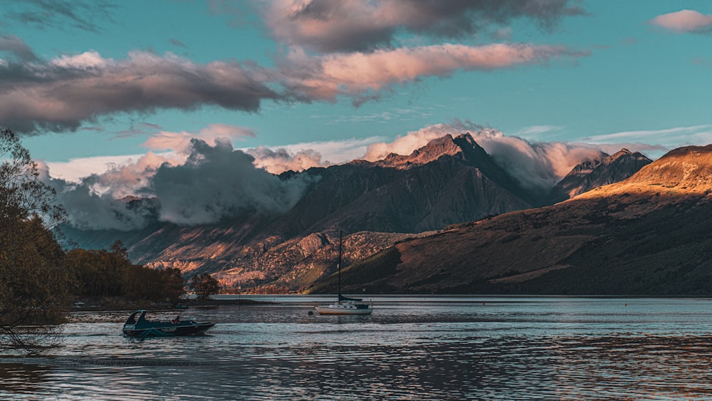 a boat floating on top of a lake surrounded by mountains