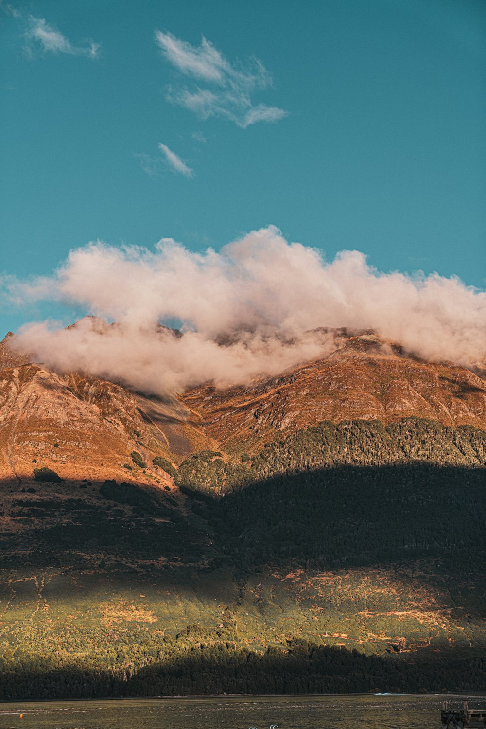 a boat floating on top of a lake next to a mountain