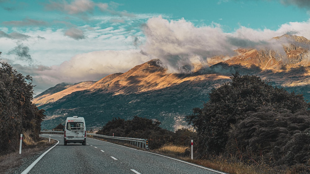 a bus driving down a road with mountains in the background