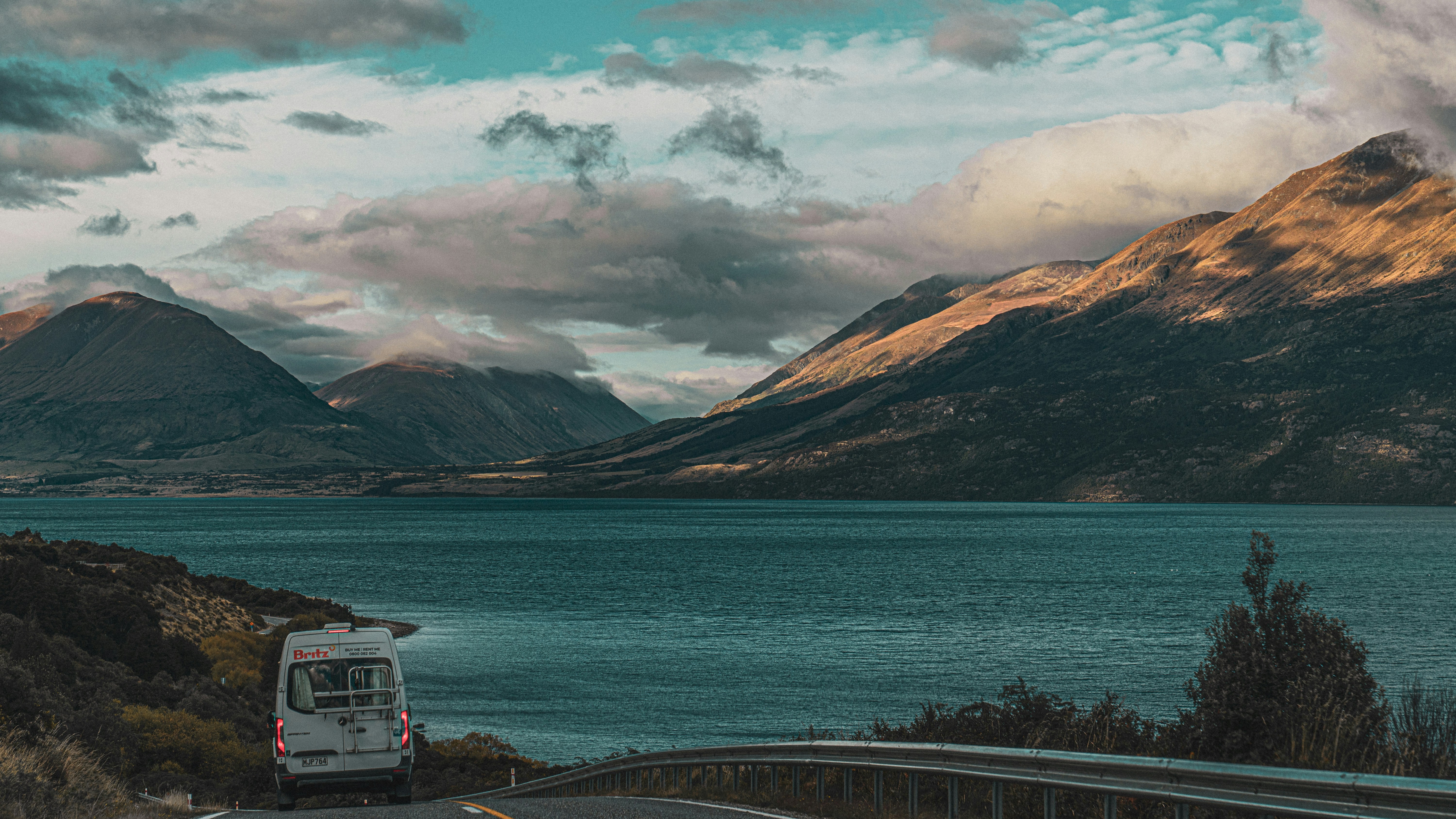 a van driving down a road next to a lake