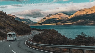 a van driving down a road next to a lake