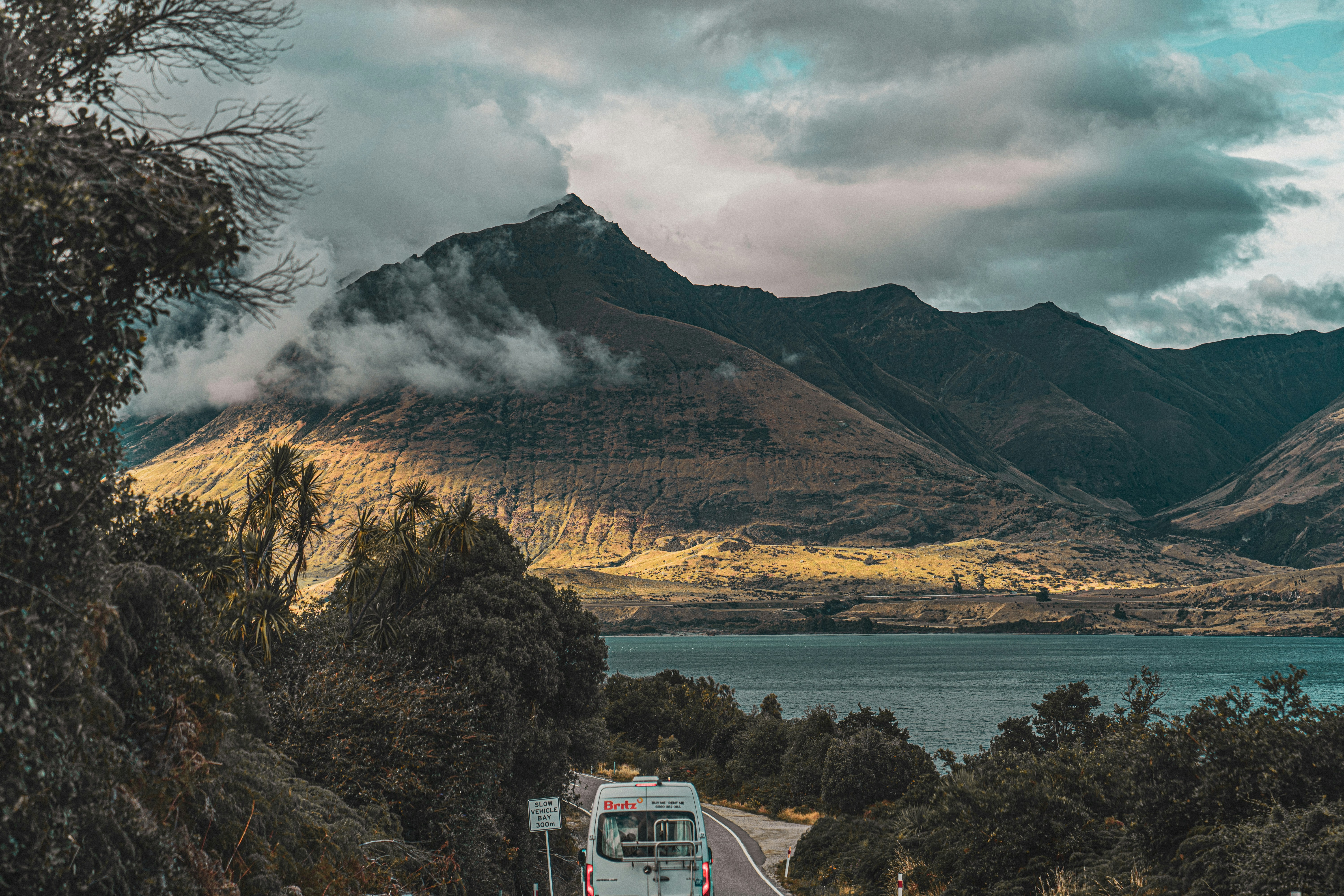 a bus driving down a road next to a mountain