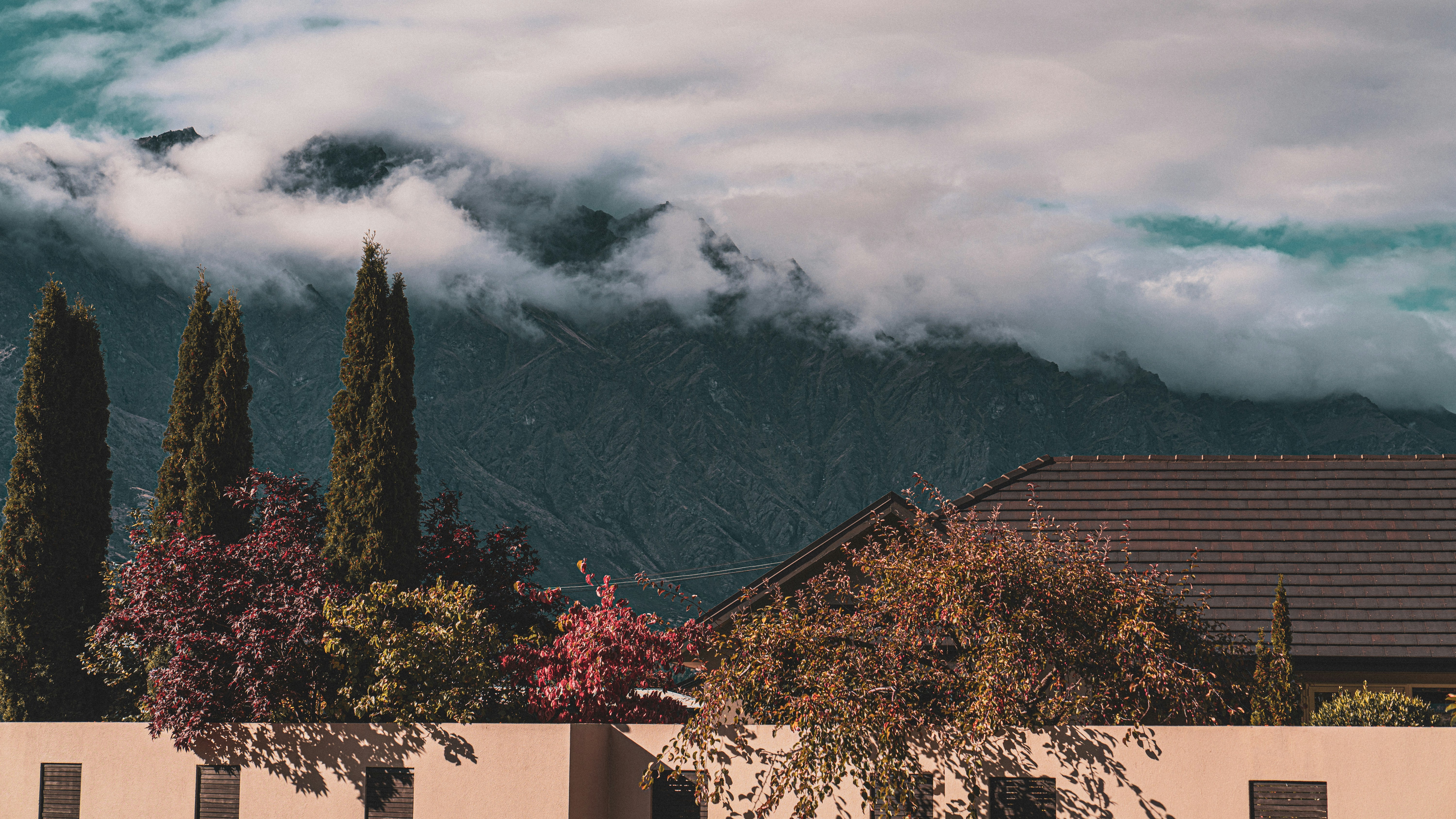 a house with mountains in the background and clouds in the sky