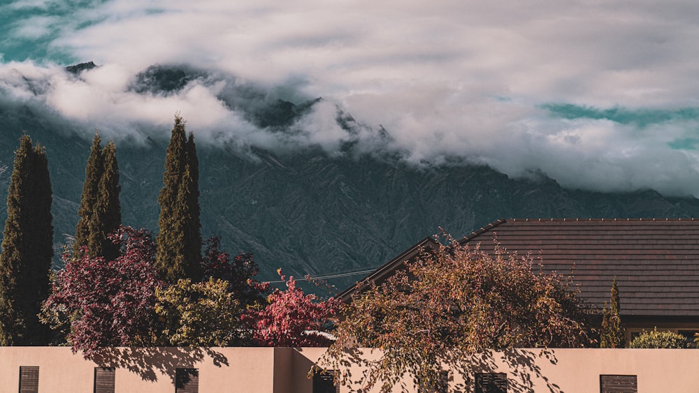 a house with mountains in the background and clouds in the sky
