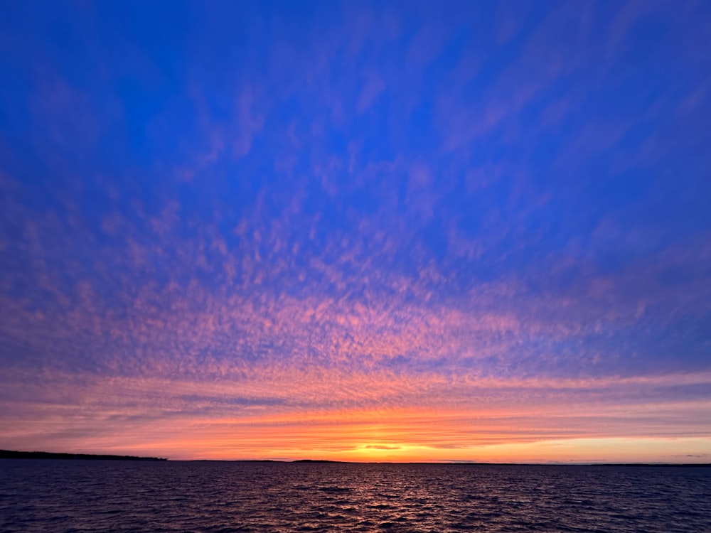 a sunset over a body of water with clouds in the sky