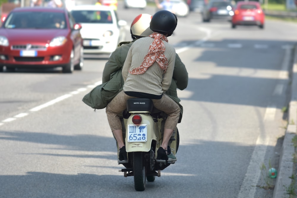 a man and a woman riding a motorcycle down a street