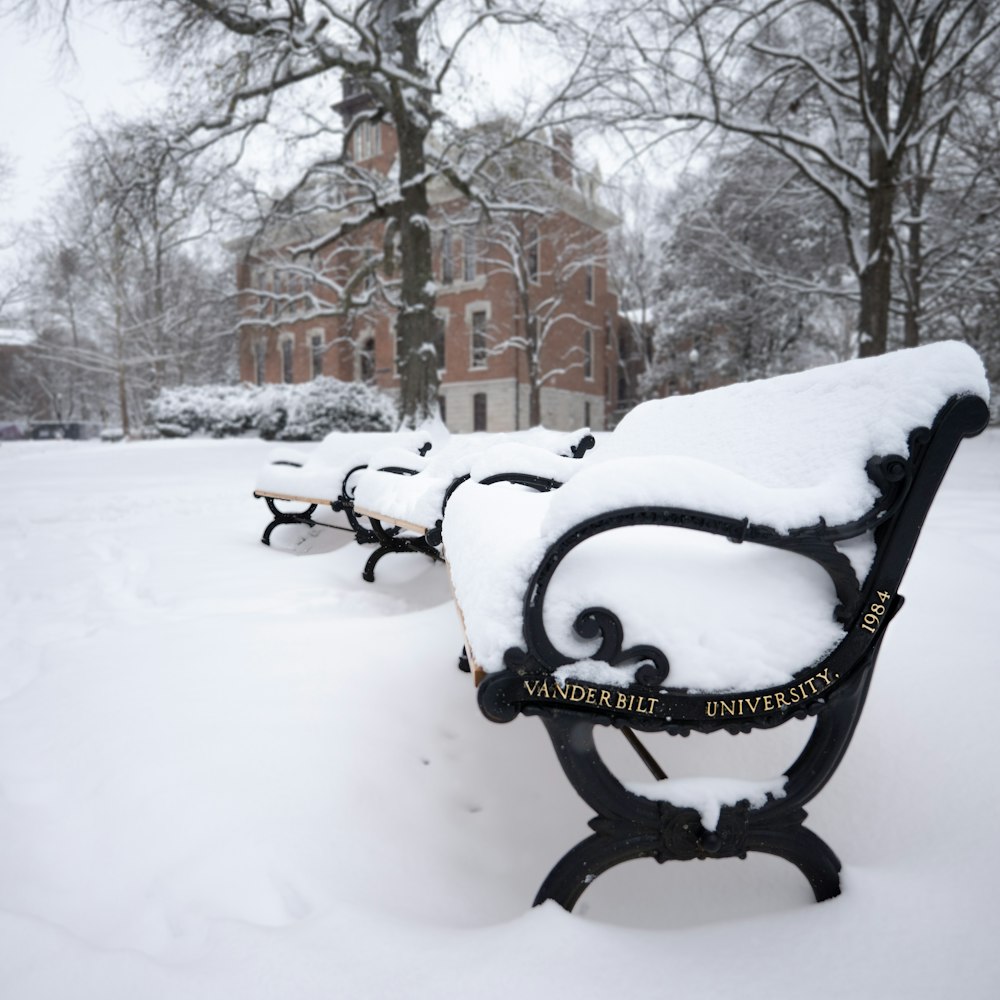 a row of benches covered in snow in front of a building