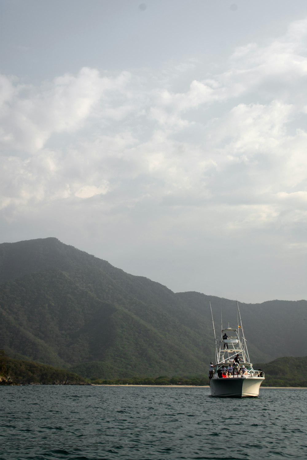 un bateau de pêche dans un plan d’eau avec des montagnes en arrière-plan