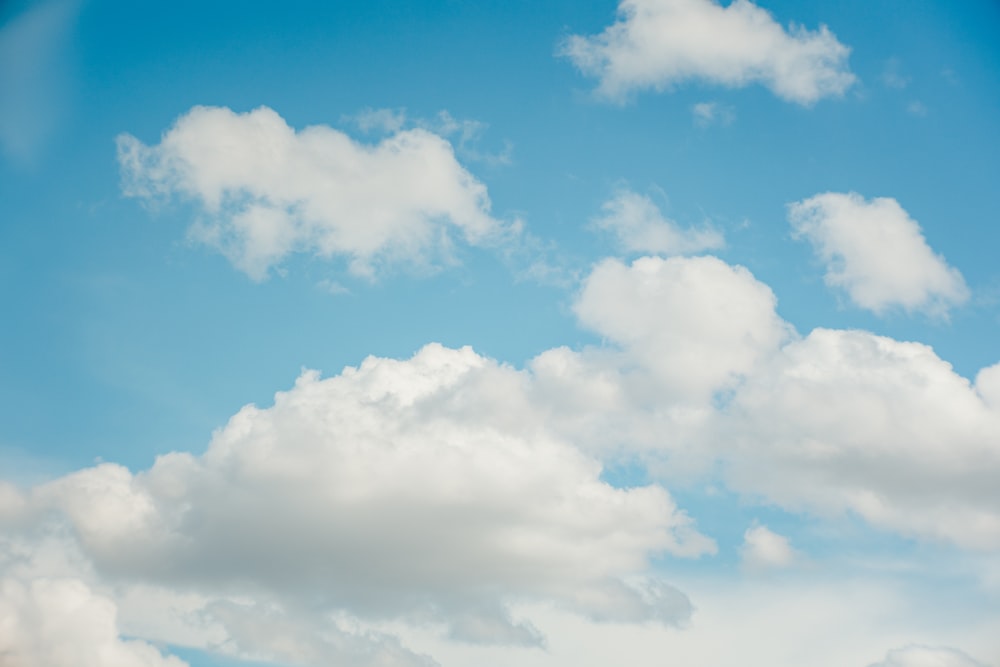 a plane flying through a cloudy blue sky