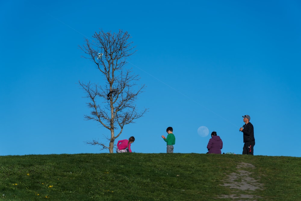 a group of people standing on top of a lush green hillside