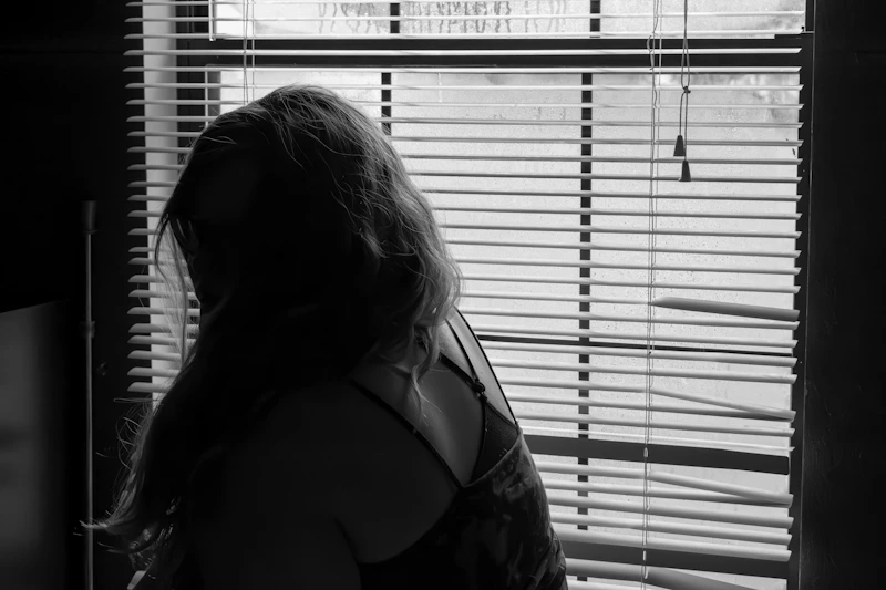 beautiful curvy woman posing by window blinds