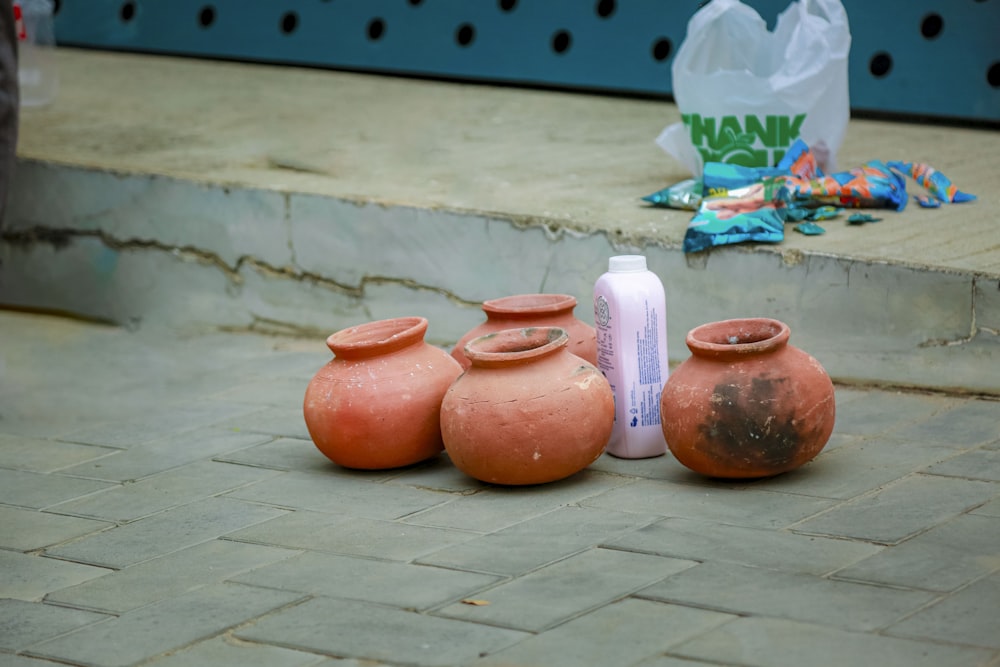 a group of clay pots sitting on a sidewalk
