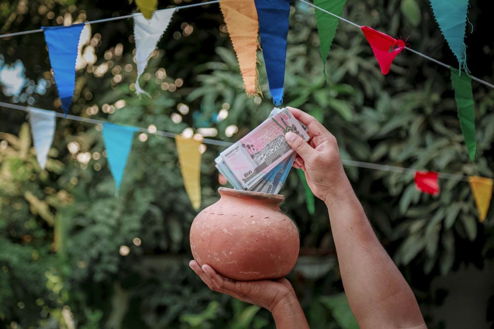 a person holding a pot with money in it