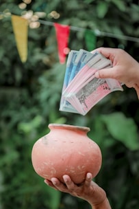 a person holding a clay pot with money coming out of it