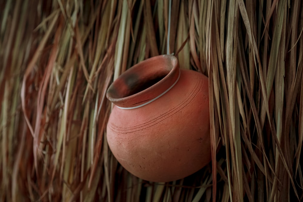 a clay pot hanging from a straw roof