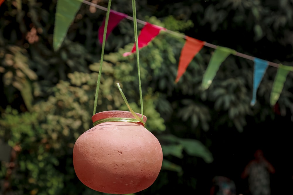 a pink pot hanging from a string with a green handle