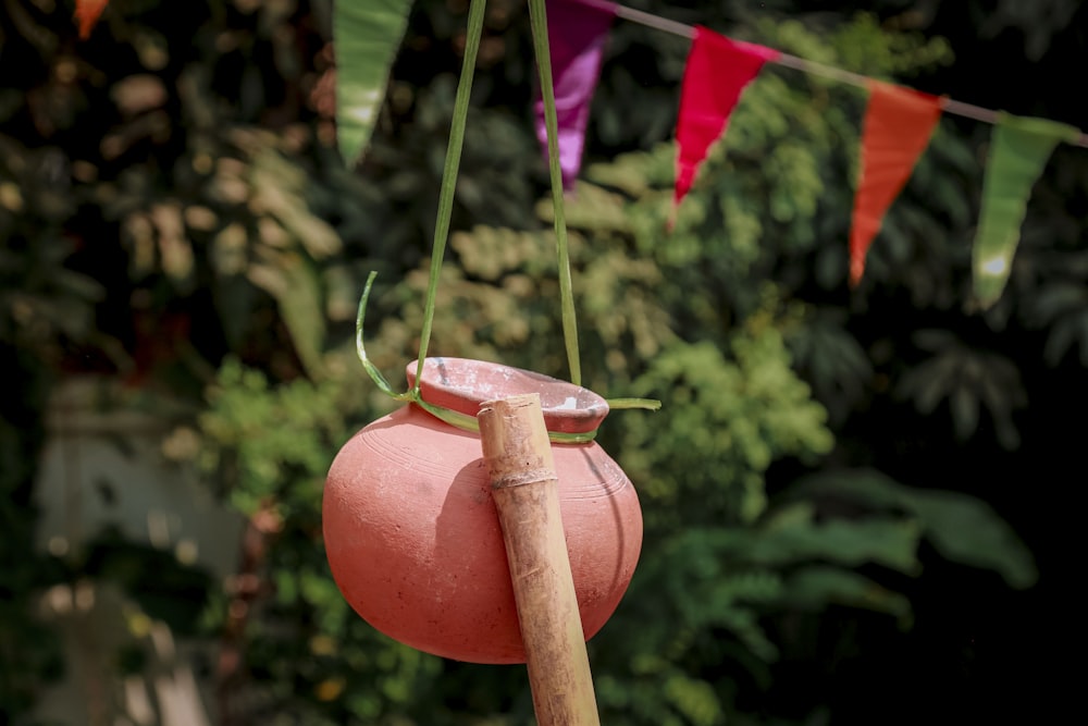a pink vase with a wooden stick hanging from it