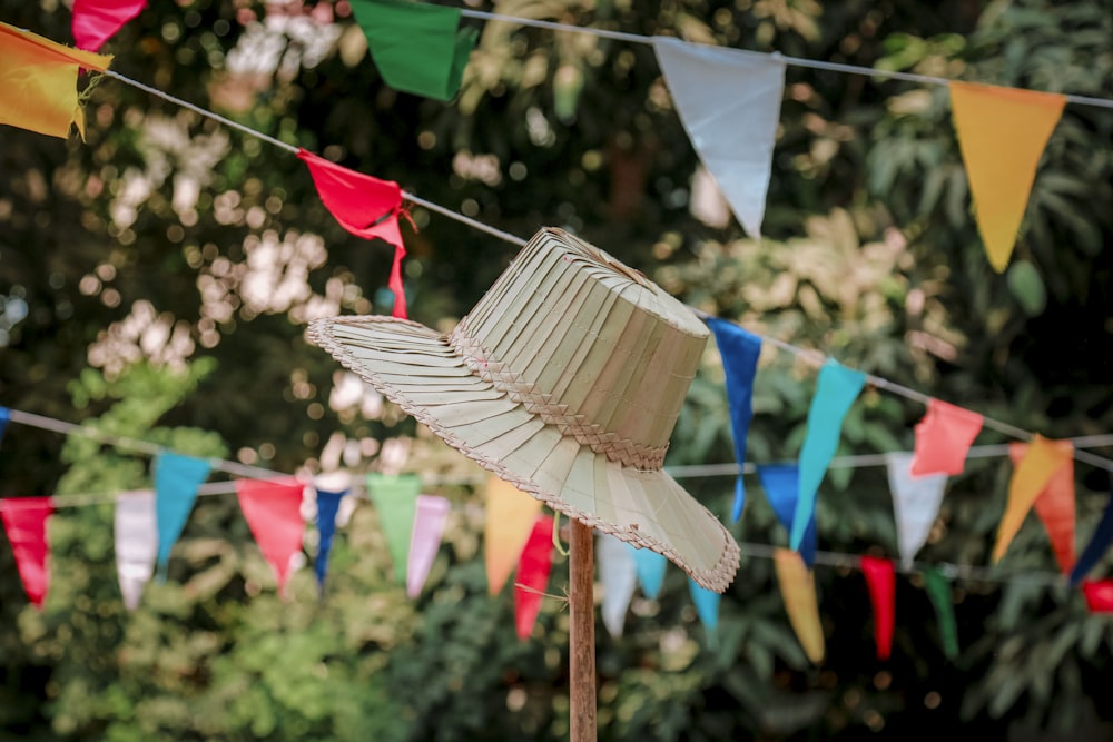 a white hat on a stick in front of colorful flags