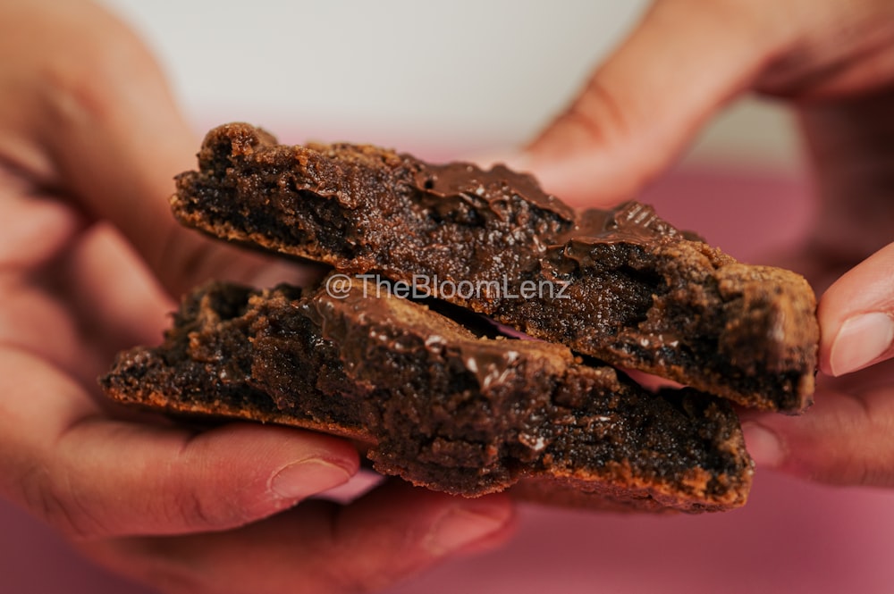 a person holding a chocolate cookie in their hands