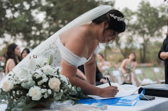 a woman in a wedding dress writing on a piece of paper