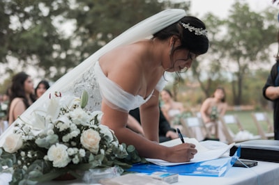 a woman in a wedding dress writing on a piece of paper