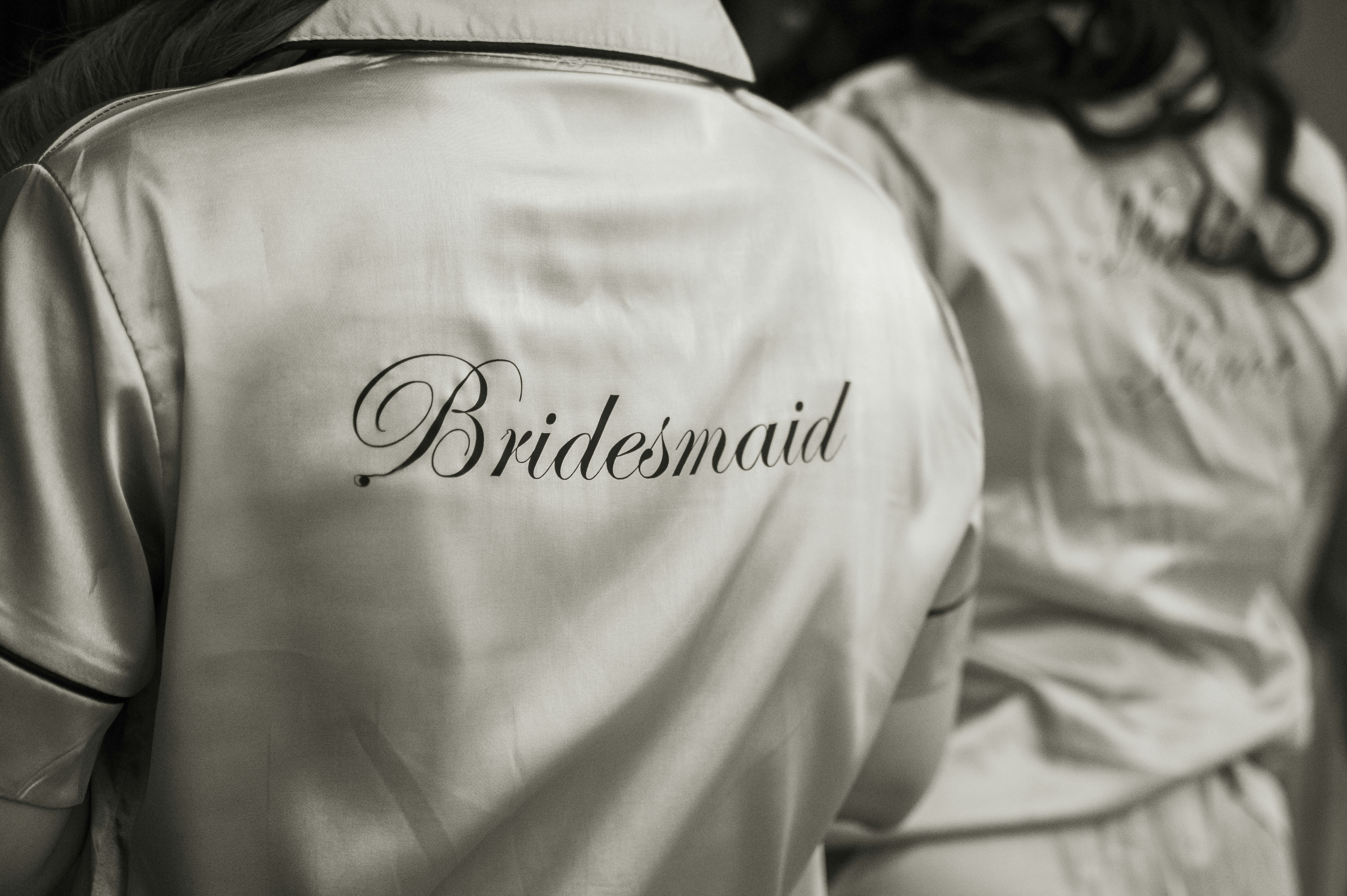 two bridesmaids in white robes with the word bridesmaid on them