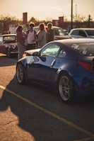 a group of people standing around a blue sports car