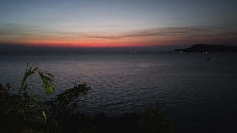 a sunset over a body of water with a small island in the distance