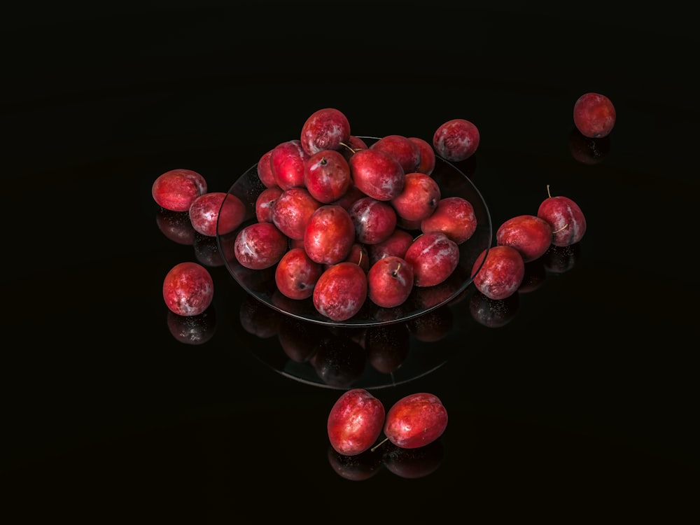 un bol en verre rempli de beaucoup de pommes rouges