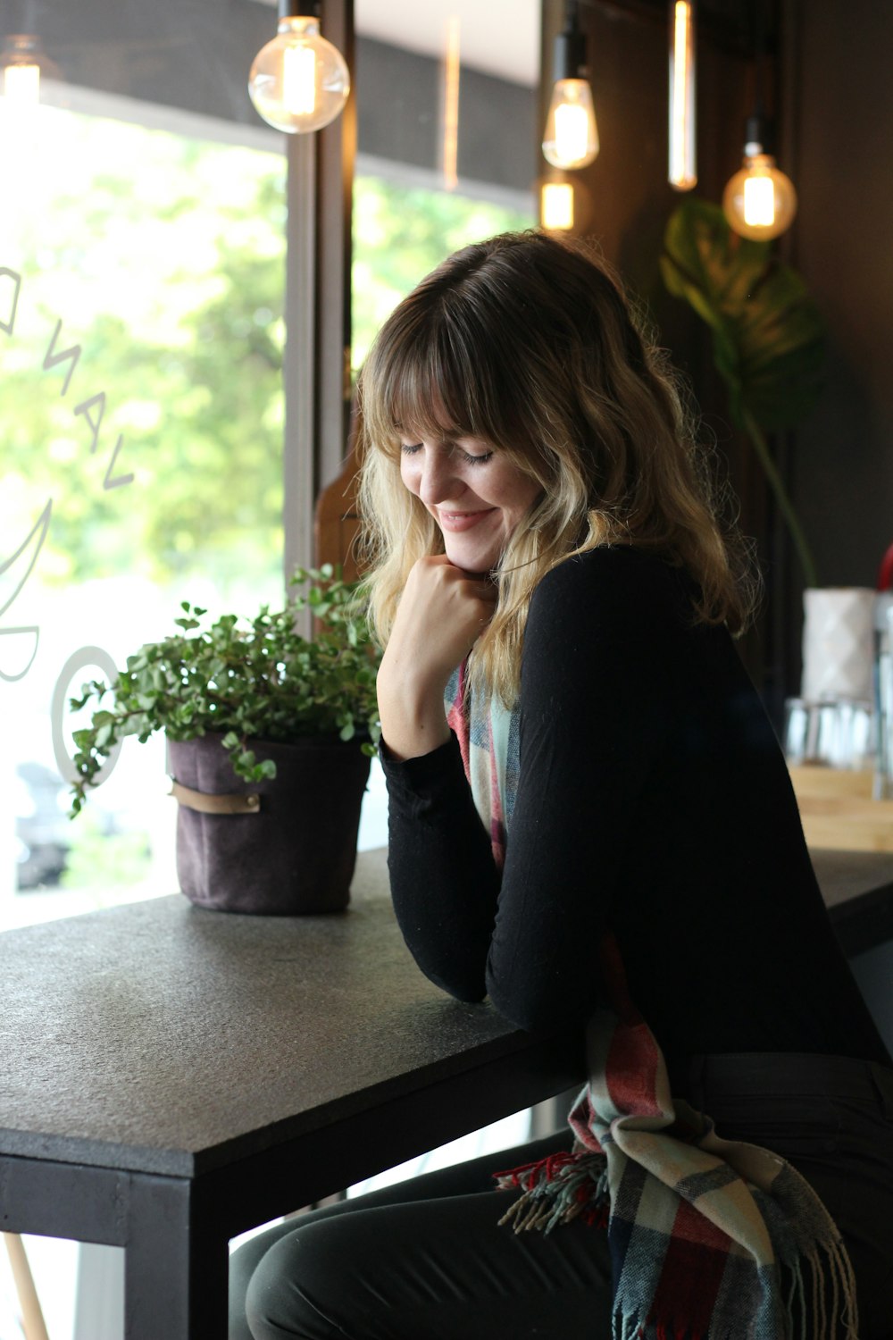 a woman sitting at a table with a potted plant