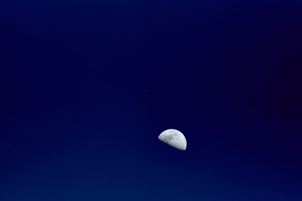 a half moon is seen in the blue sky