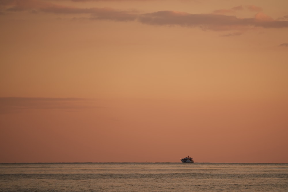 a boat is out in the ocean at sunset