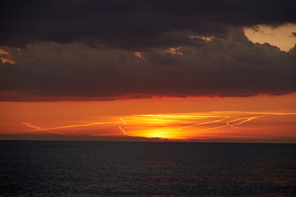 a sunset over a body of water with planes in the sky
