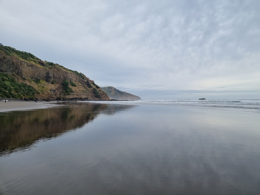 a body of water sitting next to a lush green hillside