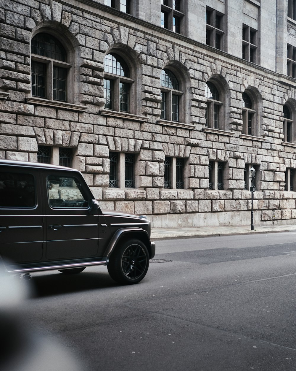 a black jeep driving down a street next to a tall building
