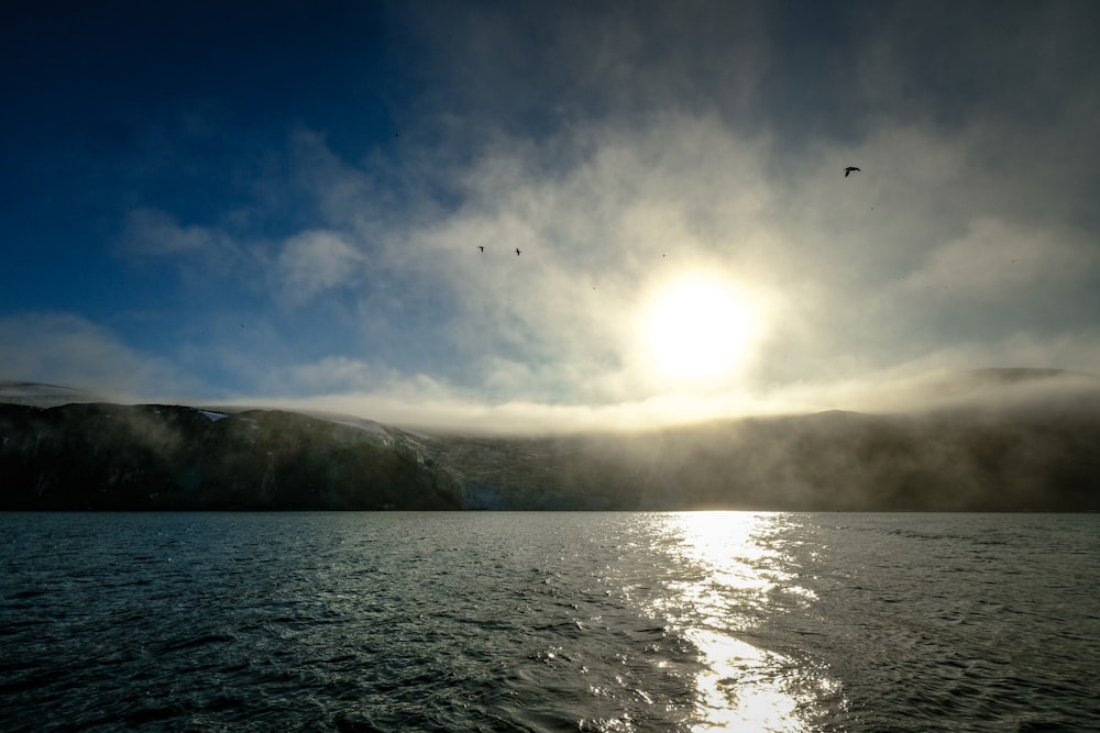 the sun shines through the clouds over a body of water