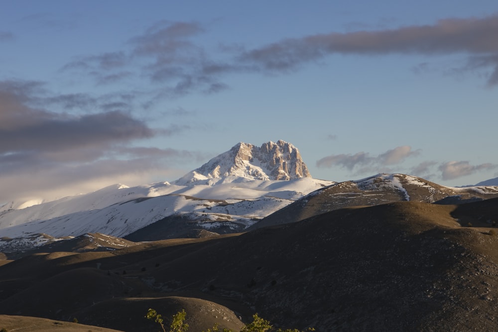 a snow covered mountain in the distance with clouds in the sky