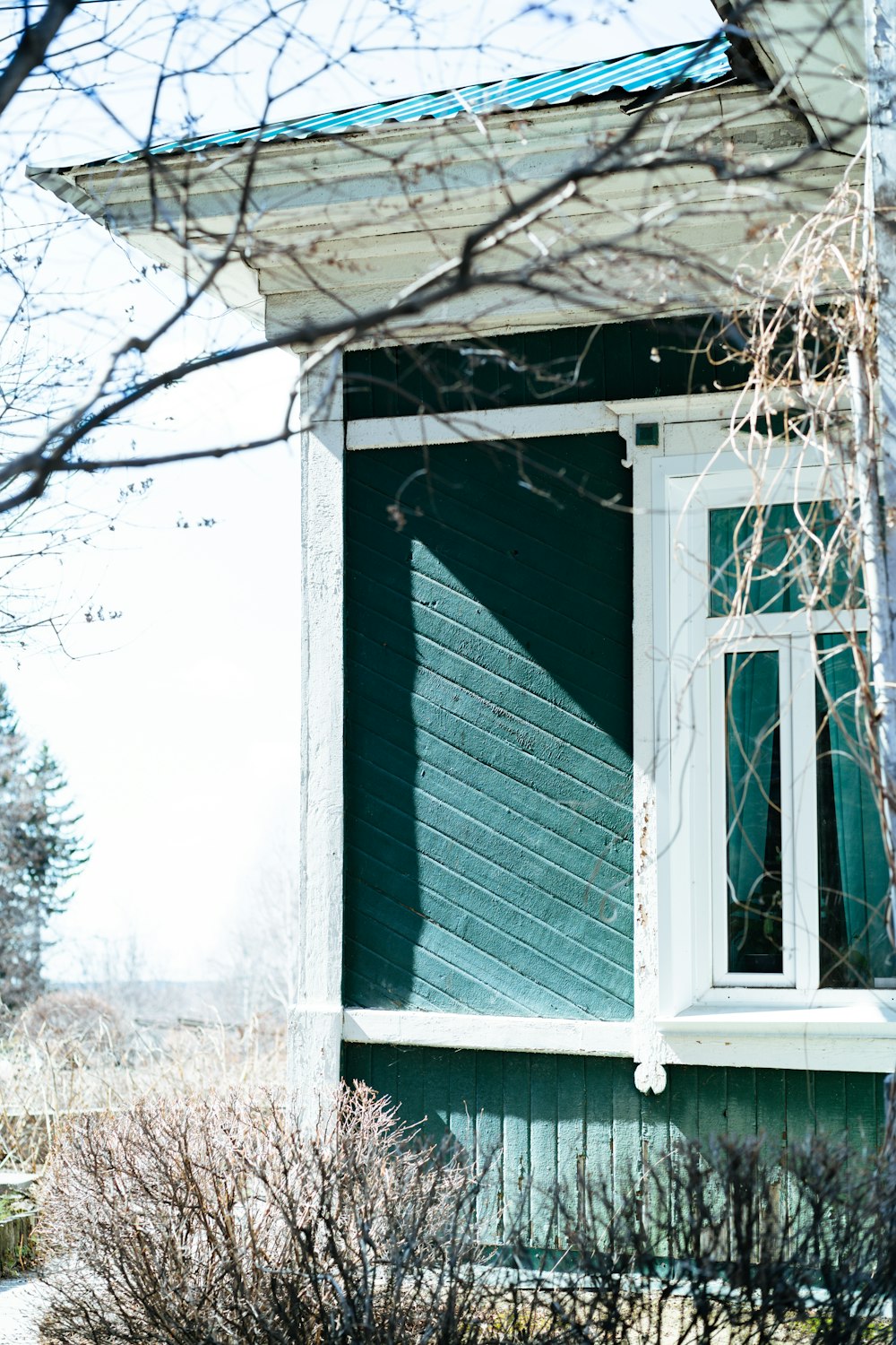 a green house with a white window and green shutters