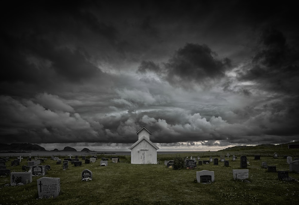 a white church in a cemetery under a cloudy sky