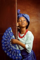 a young african american girl holding a blue fan