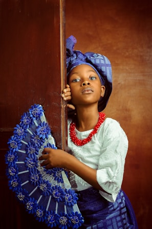 a young african american girl holding a blue fan