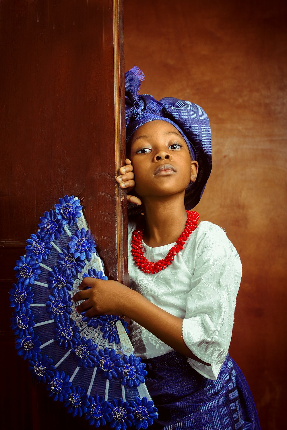 a young african american girl holding a blue fan