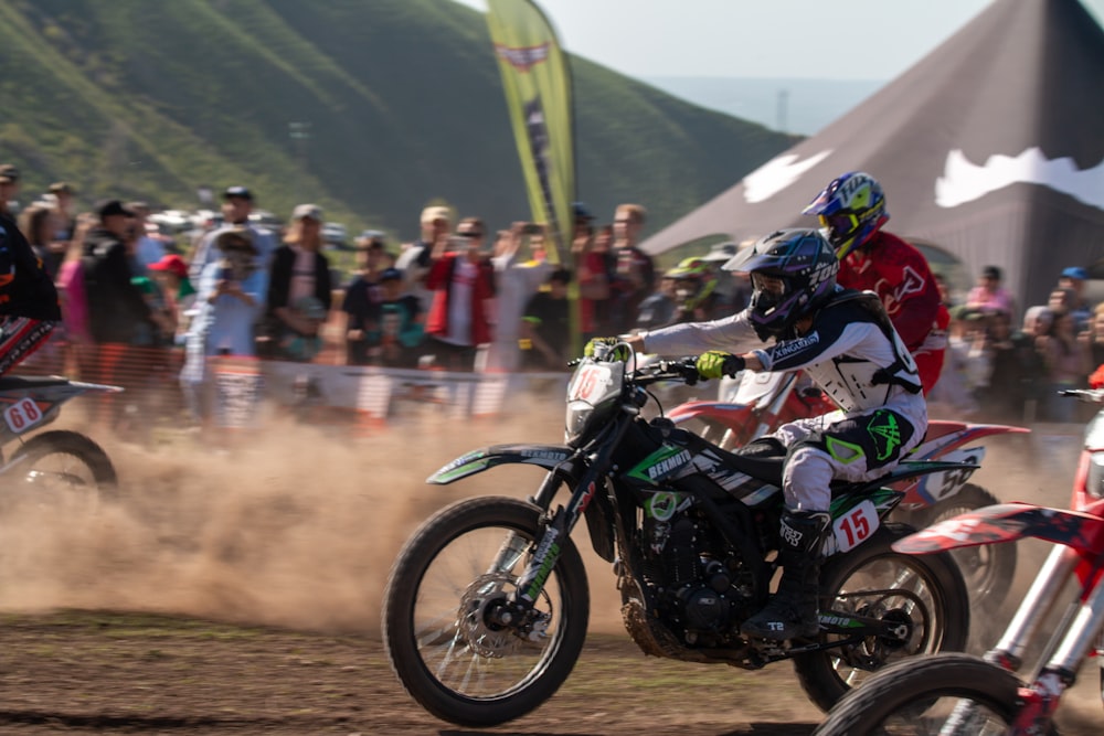 two people on dirt bikes in front of a crowd