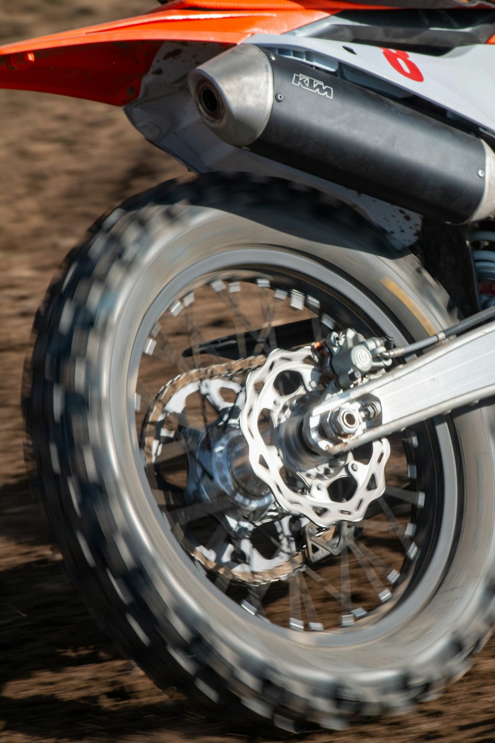 a close up of a motorcycle wheel on a dirt road