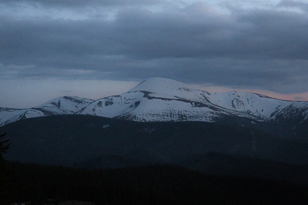 a view of a snowy mountain range at dusk