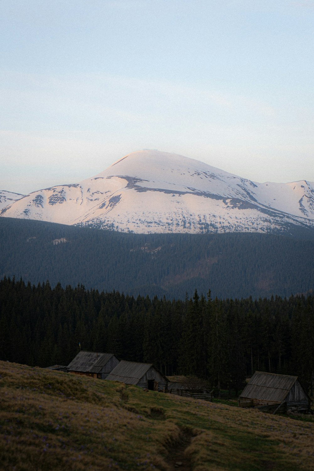 a snow covered mountain in the distance with houses in the foreground