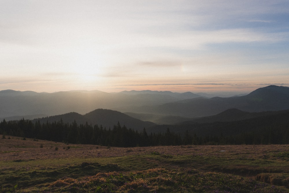 the sun is setting over the mountains in the distance