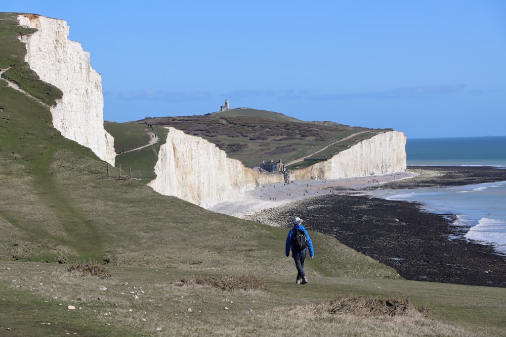 a person walking up a hill next to the ocean