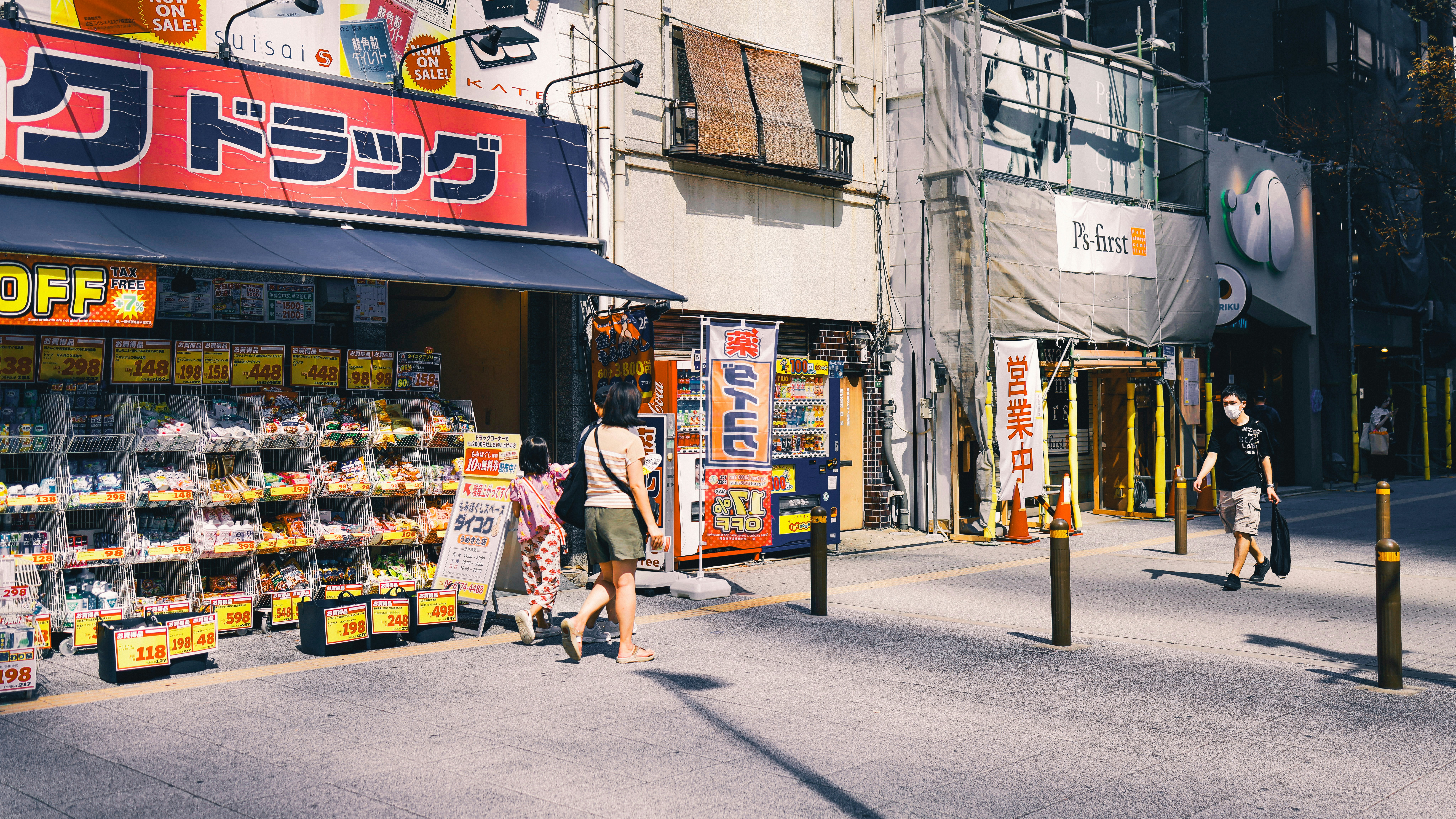 a group of people walking down a street next to a store